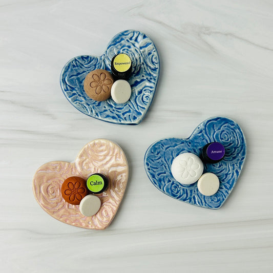 Three heart-shaped ceramic plates with various items on a light gray surface